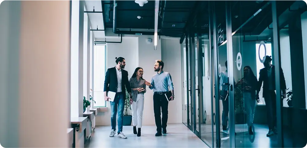 Three employees walk down an office hallway